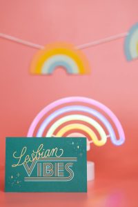 Vibrant 'Lesbian Vibes' card with neon rainbow on pink background.